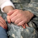 soldier holding girlfriends hand, farewell before military service