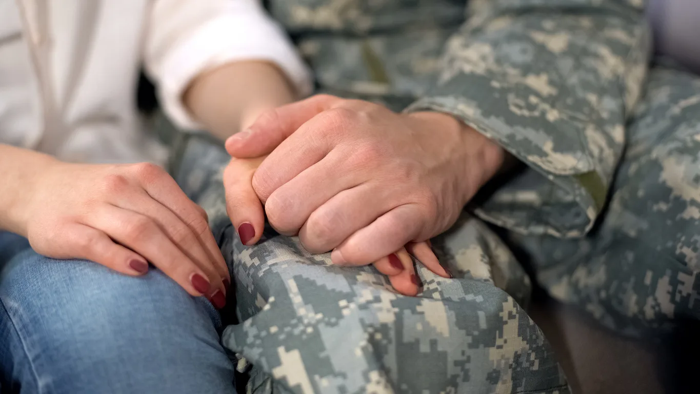 soldier holding girlfriends hand, farewell before military service