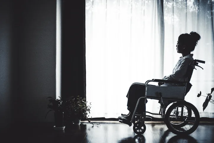 woman sitting in a wheelchair looking out the window